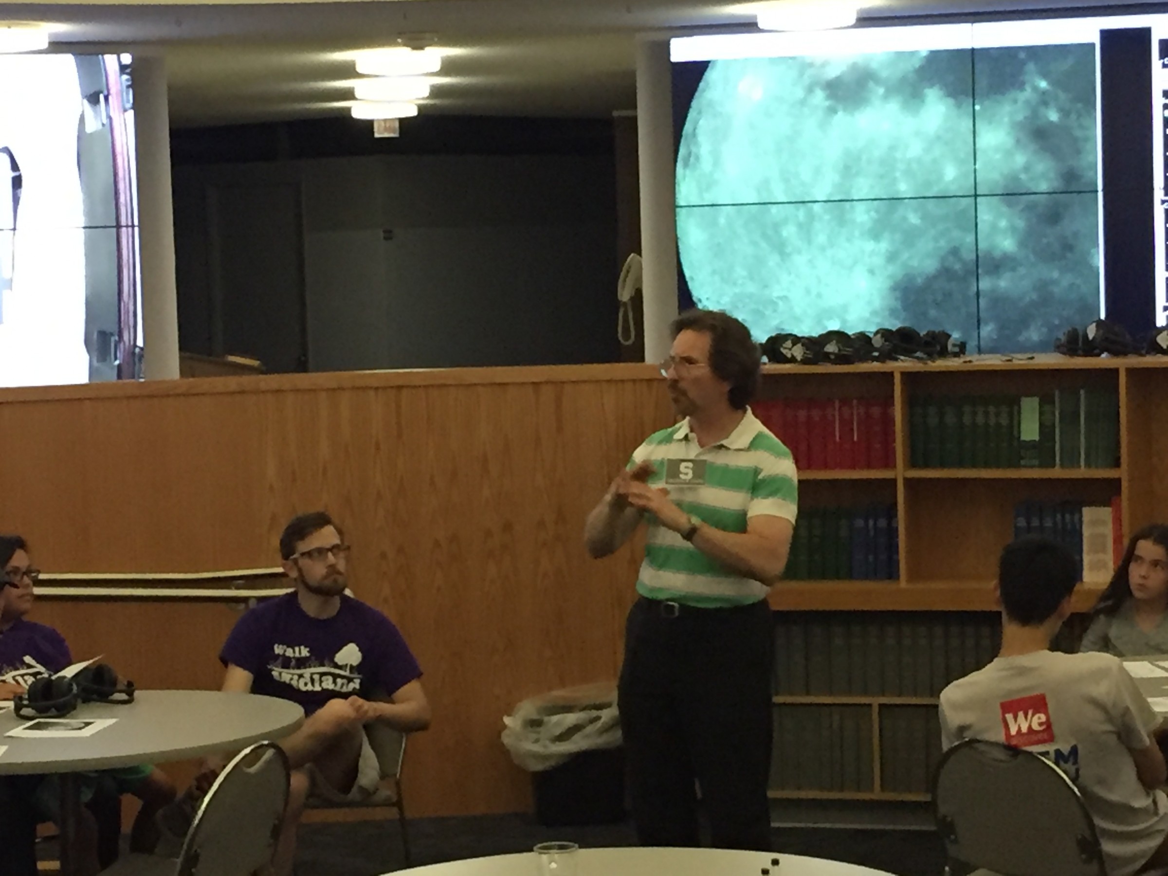 Researcher explains astronomy lesson with moon photo in background