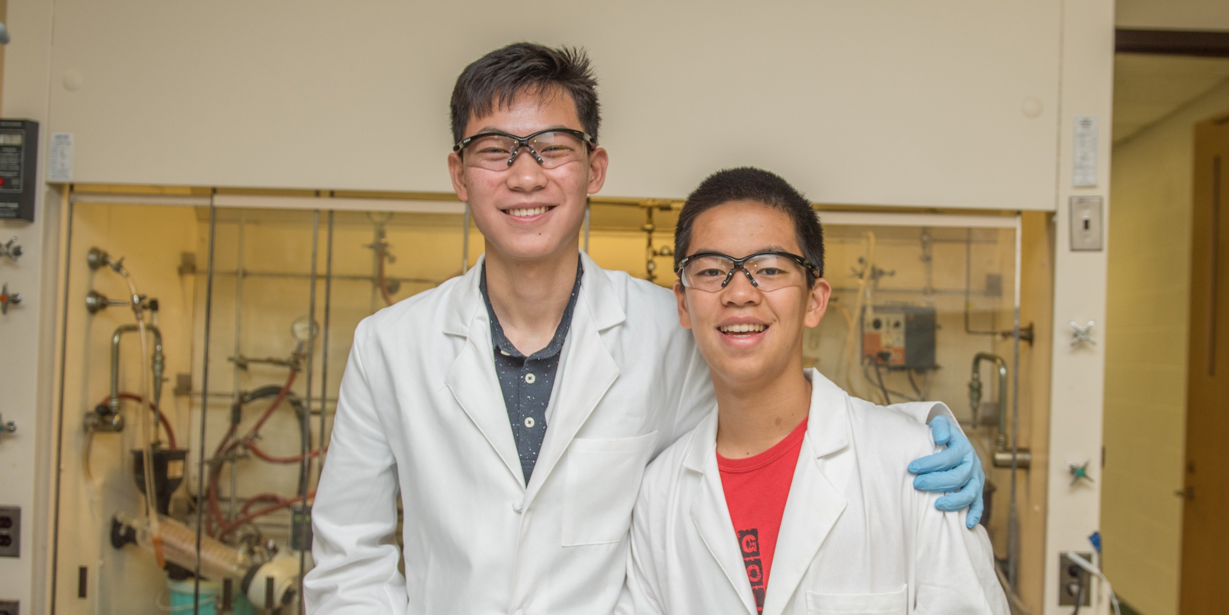 Two students in lab coats pose for photo
