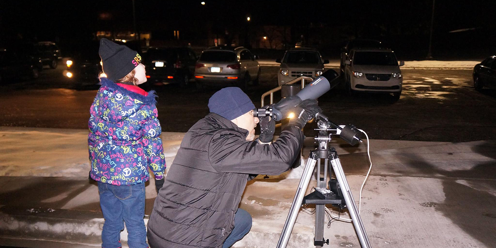 Instructor showing child how to use telescope during evening educational event