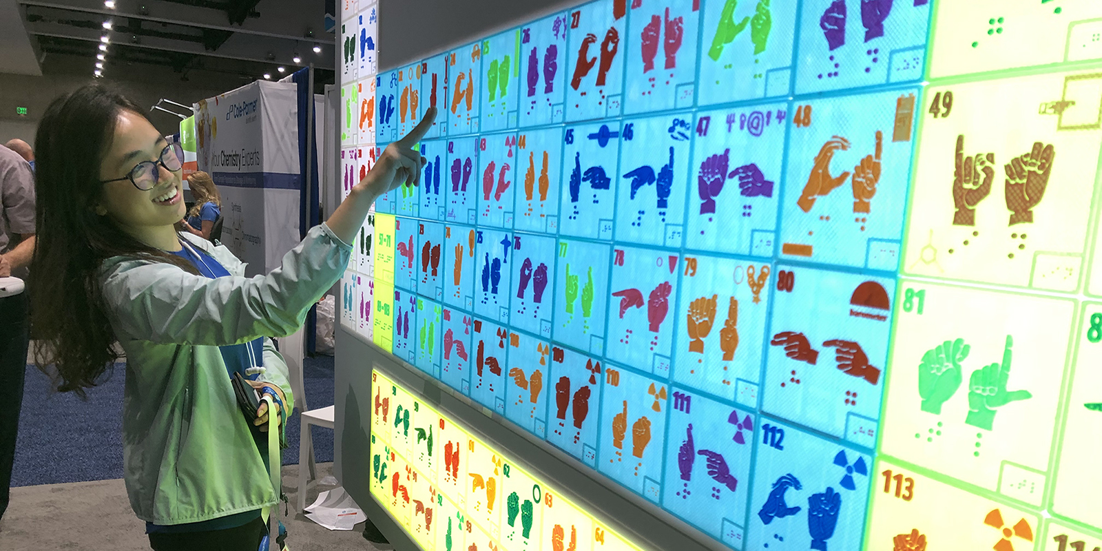 Woman standing in front of periodic table display